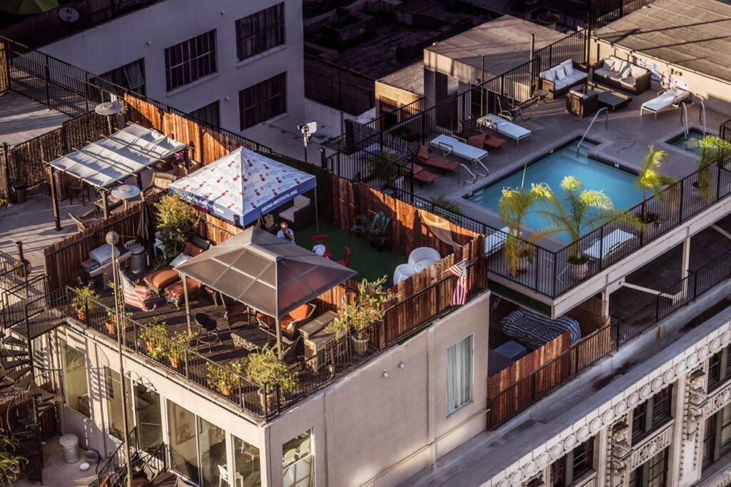 An aerial view of a stylish rooftop terrace with a pool and seating area in a city setting.